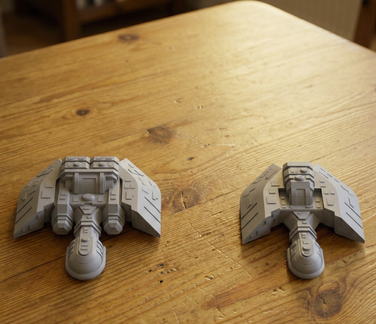 Two gray model spaceships on a wooden surface